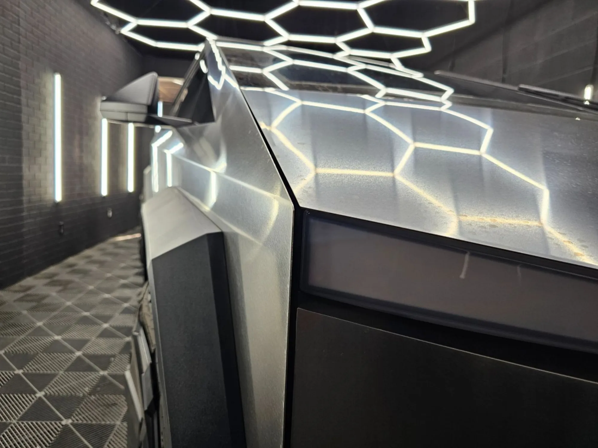 Close-up of Tesla Cybertruck panels reflecting studio hex lights
